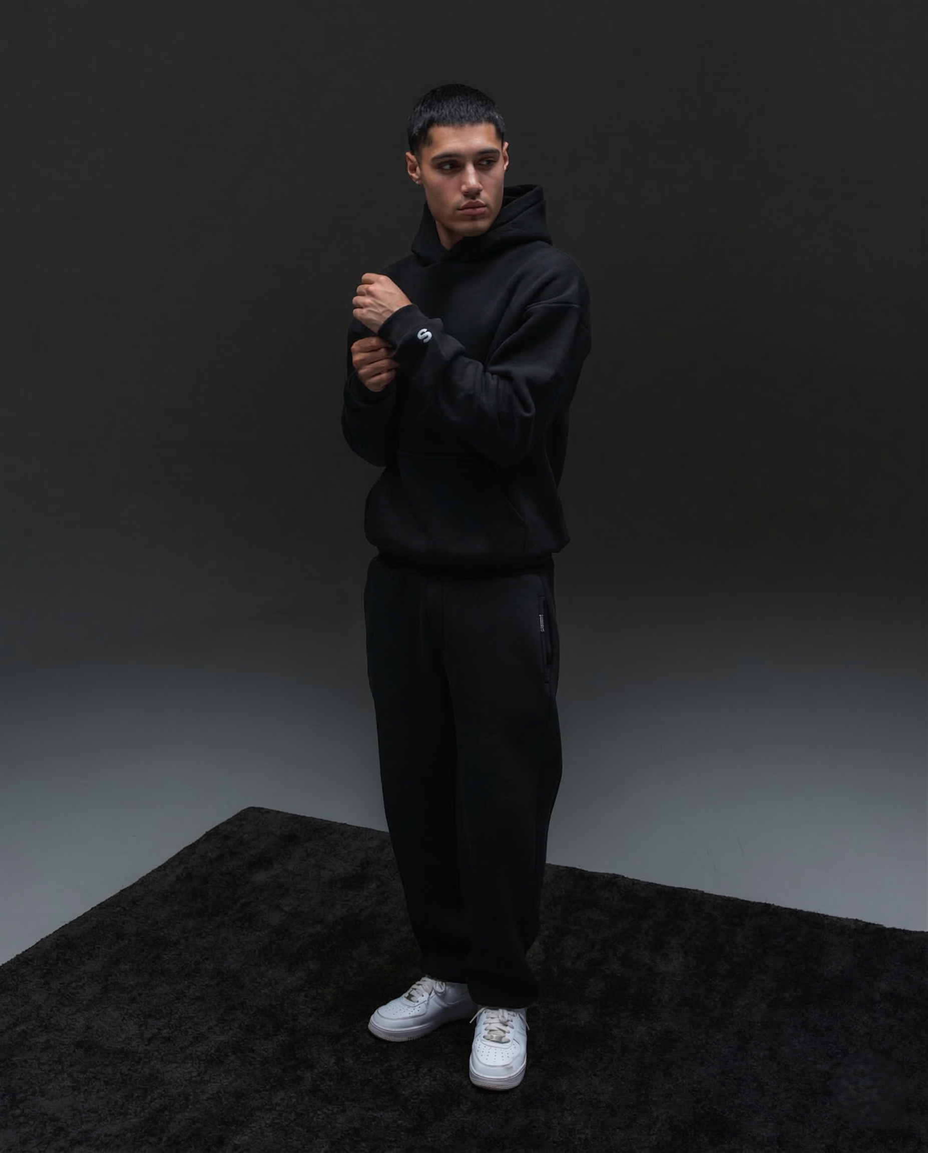 Stamtement model trägt ein basic hoodie und ein open leg jogger in schwarz